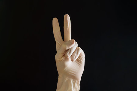 Hand in white latex glove in V sign peace or victory gesture