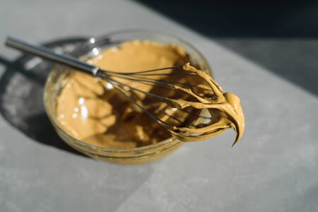 Whipping instant coffee for dalgona drink with whisk. Hard sun light, concrete backgroundの写真素材