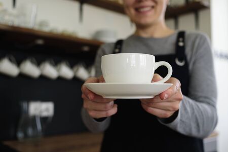 Woman waitress with cup smiling in cafe. Local businessの写真素材