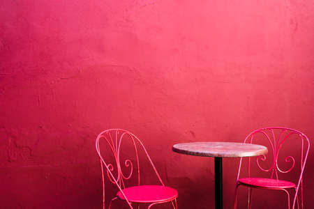 Pink street cafe table with chairs on pink building wallの写真素材