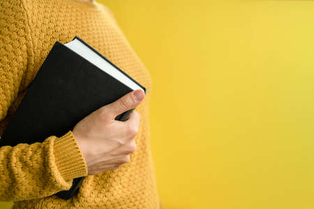 Woman student in sweater with books on yellowの写真素材