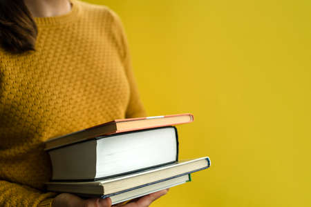 Woman student in sweater with books on yellowの写真素材
