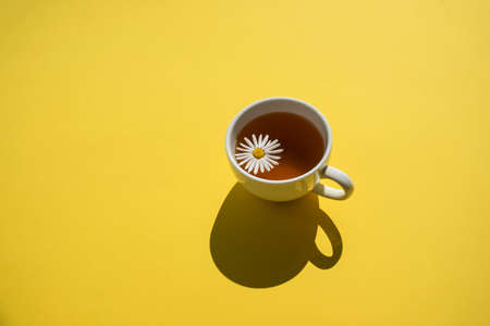 Cup of herbal chamomile tea on yellow at sunny dayの写真素材
