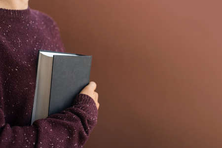 Woman student in sweater with books on brownの写真素材