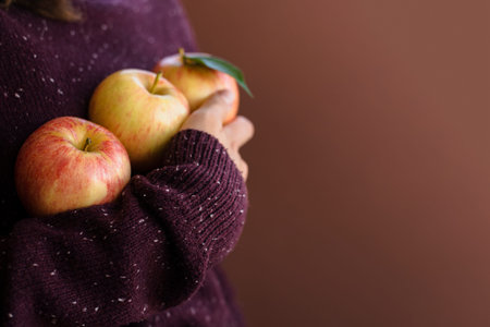 Happy woman gardener in brown sweater holding fresh apples