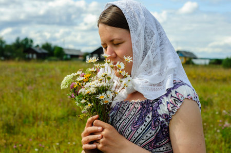 Young woman in vintage clothes with wildflowers bouquet in country. Cottagecore