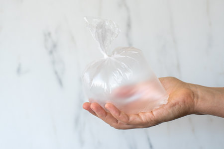Hand holding inflated plastic bag. Microplastic pollution conceptの写真素材