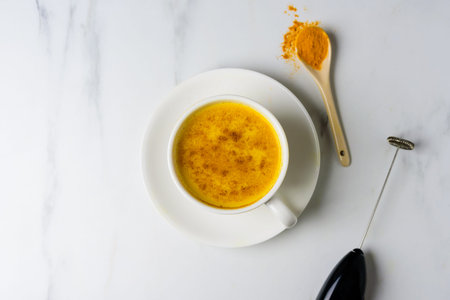 Turmeric golden spicy latte in white cup on marble table