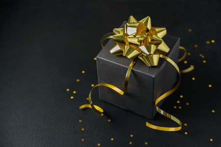 Black gift box with golden bow and stars confettiの写真素材