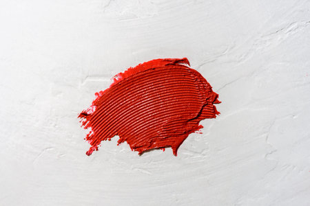 Smear or swatche of red color lipstick on white