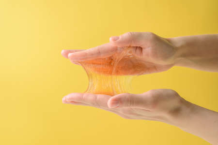 Hands with sticky sugar wax piece on yellowの写真素材