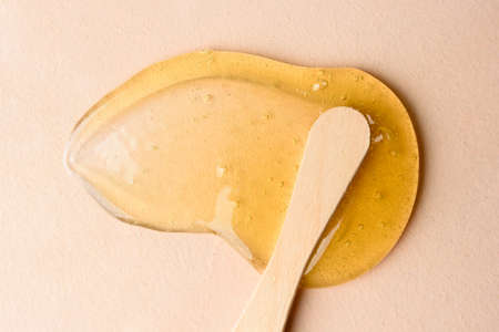 Liquid sugar wax smear with spatula on beige backgroundの写真素材