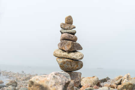 Stack or pile of stones cairn on foggy beach. Balance and harmony conceptの写真素材