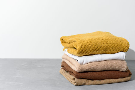 Stack of yellow and beige clothes on grey surface