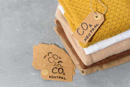 Clothes in stack with carbon emission paper recycled labelの写真素材