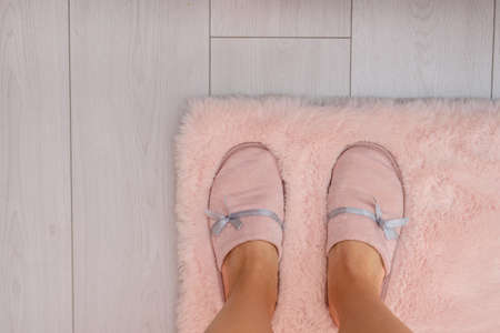 Legs in pink slippers on fur carpet and white floorの写真素材