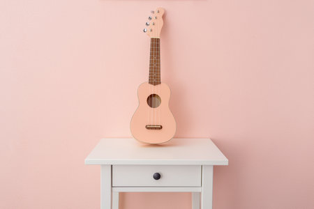 Pink ukulele near pink wall on bedside tableの写真素材