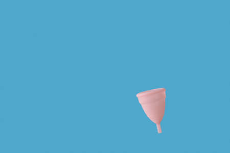 Pink reusable menstrual cup on blue backgroundの写真素材