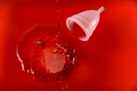 Pink reusable menstrual cup on red blood liquid backgroundの写真素材