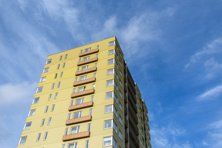 Tall green residential building against blue sky with cloudsの写真素材