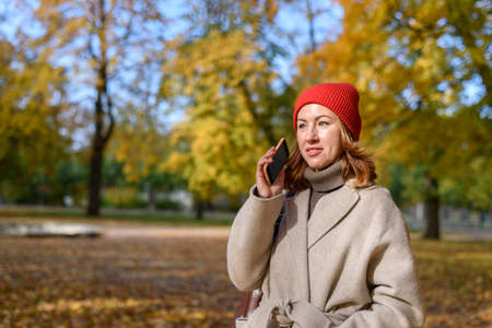 Woman talking on mobile phone at autumn parkの写真素材
