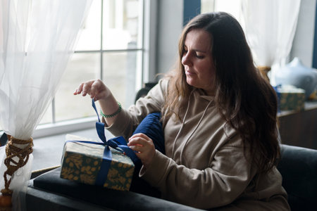 Woman wrapping christmas gifts at living room with decorationsの写真素材