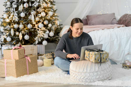 Woman with laptop, Christmas gifts and decorations. Buying or ordering onlineの写真素材