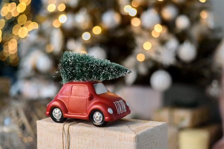 Unrecognised red toy car with Christmas tree on roof standing on gift boxの写真素材