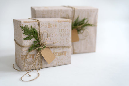 Wrapped in craft paper gift boxes with empty tag on light grey background. Neutral, eco recycled...
