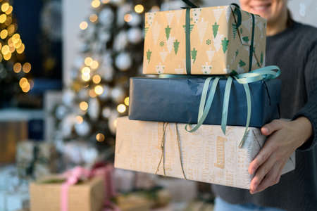 Woman holding stack gift boxes with Christmas decorationsの写真素材