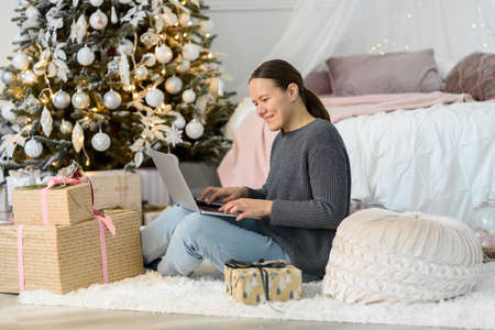 Woman with laptop, Christmas gifts and decorations. Buying or ordering onlineの写真素材