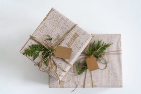Wrapped in craft paper gift boxes with empty tag on light grey background. Neutral, eco recycled...