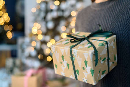 Woman in sweater holding gift boxes with Christmas decorationsの写真素材