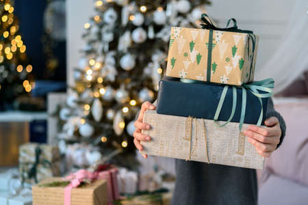 Woman holding stack gift boxes with Christmas decorationsの写真素材