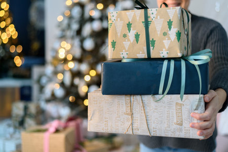 Woman holding stack gift boxes with Christmas decorationsの写真素材