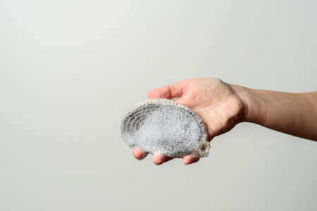 Hand holding natural reusable handmade knitted jute wash cloth with soap foamの写真素材
