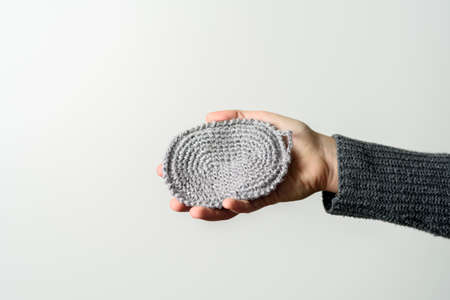 Hand holding natural reusable handmade knitted jute wash clothの写真素材