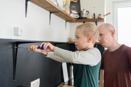 Father and son doing house renovations together. Using screwdriver. Dad teaching child to use tools