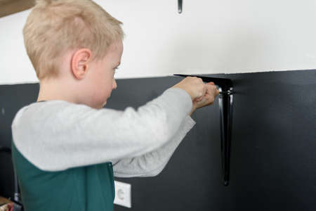 Boy child using screwdriver to renovation works at home kitchenの写真素材