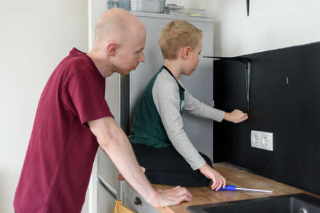 Father and son doing house renovations together. Using screwdriver. Dad teaching child to use toolsの写真素材