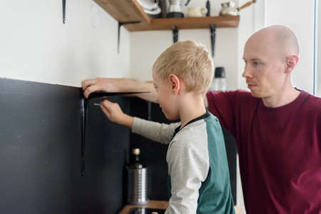 Father and son doing house renovations together. Using screwdriver. Dad teaching child to use toolsの写真素材