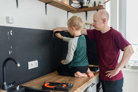 Father and son doing house renovations together. Using screwdriver. Dad teaching child to use toolsの写真素材