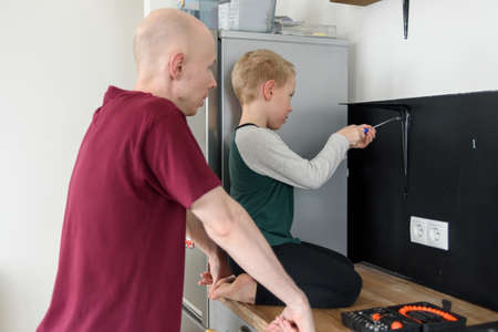 Father and son doing house renovations together. Using screwdriver. Dad teaching child to use toolsの写真素材