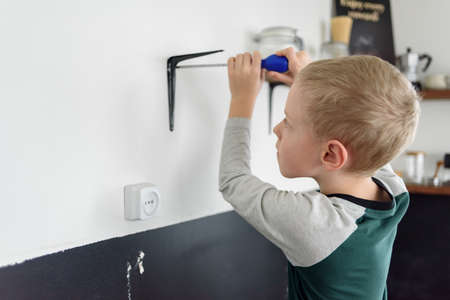 Boy child using screwdriver to renovation works at home kitchenの写真素材