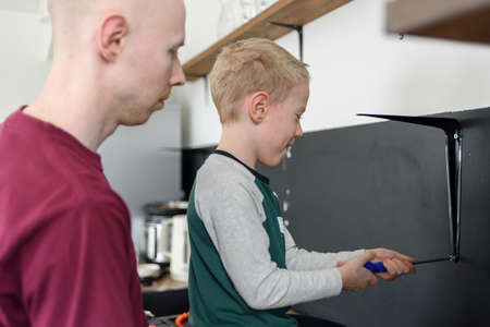 Father and son doing house renovations together. Using screwdriver. Dad teaching child to use toolsの写真素材