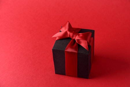 Red gift box with red bow on red backgroundの写真素材