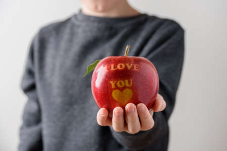 Child holding red apple with text I Love You as giftの写真素材
