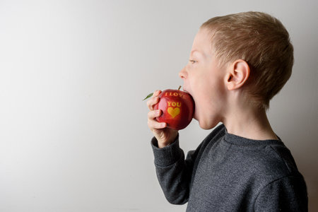 Child eating red apple with text I Love You. Healthy giftの写真素材