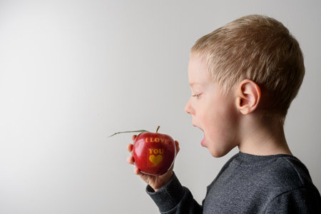 Child eating red apple with text I Love You. Healthy giftの写真素材