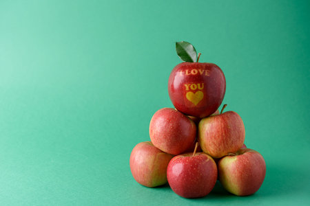Red apple with text I Love You on green background